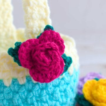 A crochet basket with a rose applique on the side.