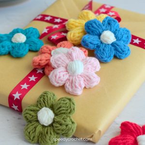 Crochet puff flowers displayed on a brown paper wrapped gift.