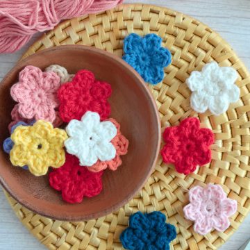 Crochet flowers in a bowl on a placemat.
