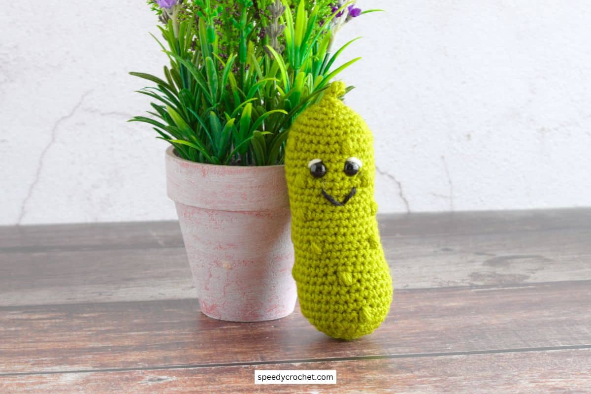 Small crochet pickle leaning on a flower pot.