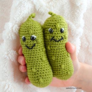 Two crochet pickles with smiling faces.