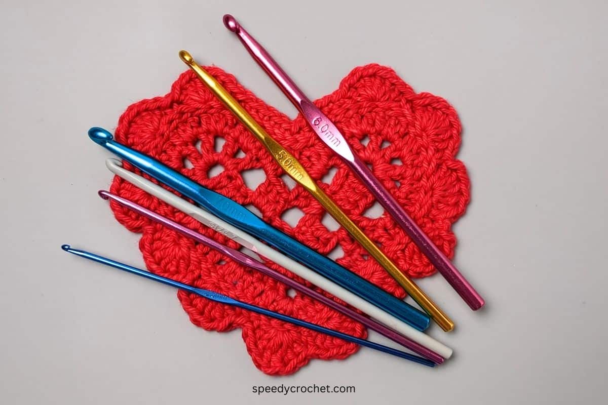 Crochet hooks on a red crochet heart.