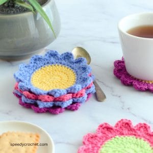 A set of crochet flower coasters in pink, blue and purple.