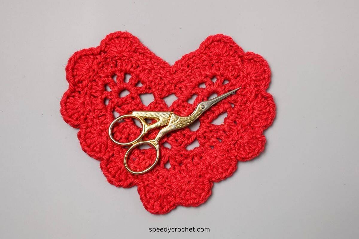 Stork scissors on a red crochet heart.