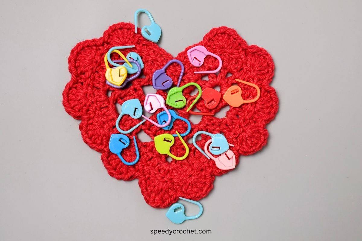 Stitch markers on a red crochet heart.