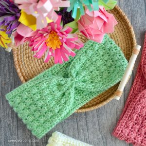 A green crochet headband ear warmer on a tray.