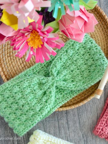 A green crochet headband ear warmer on a tray.