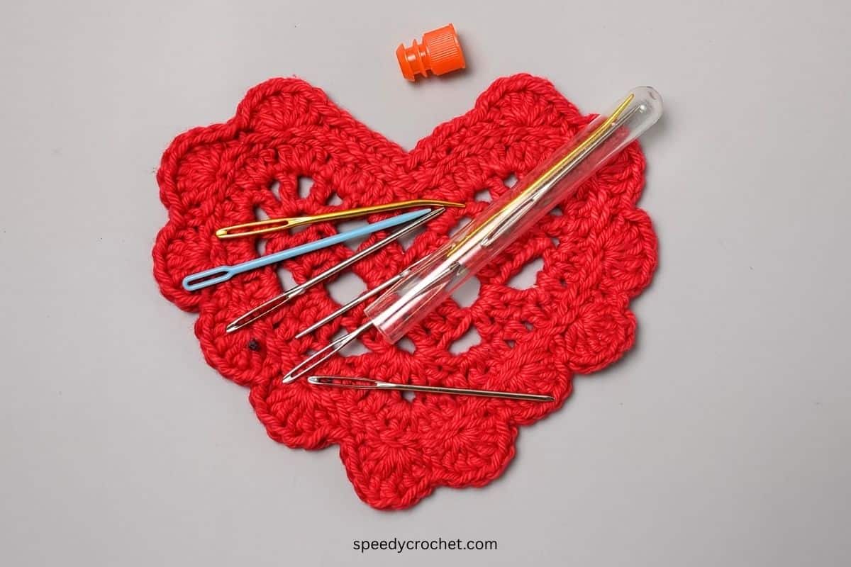 Yarn needles on a red crochet heart.