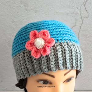 A blue and grey crochet beanie with a flower.