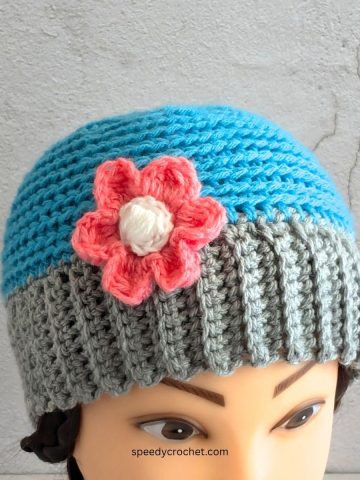 A blue and grey crochet beanie with a flower.