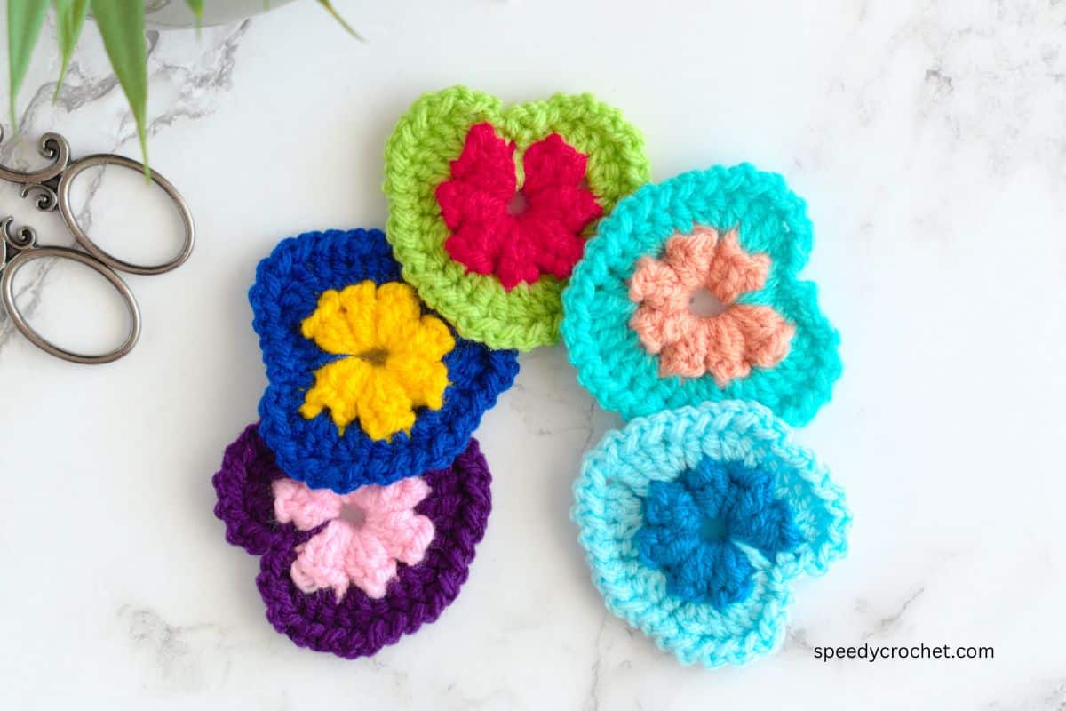 Top down view of five crochet heart motifs.