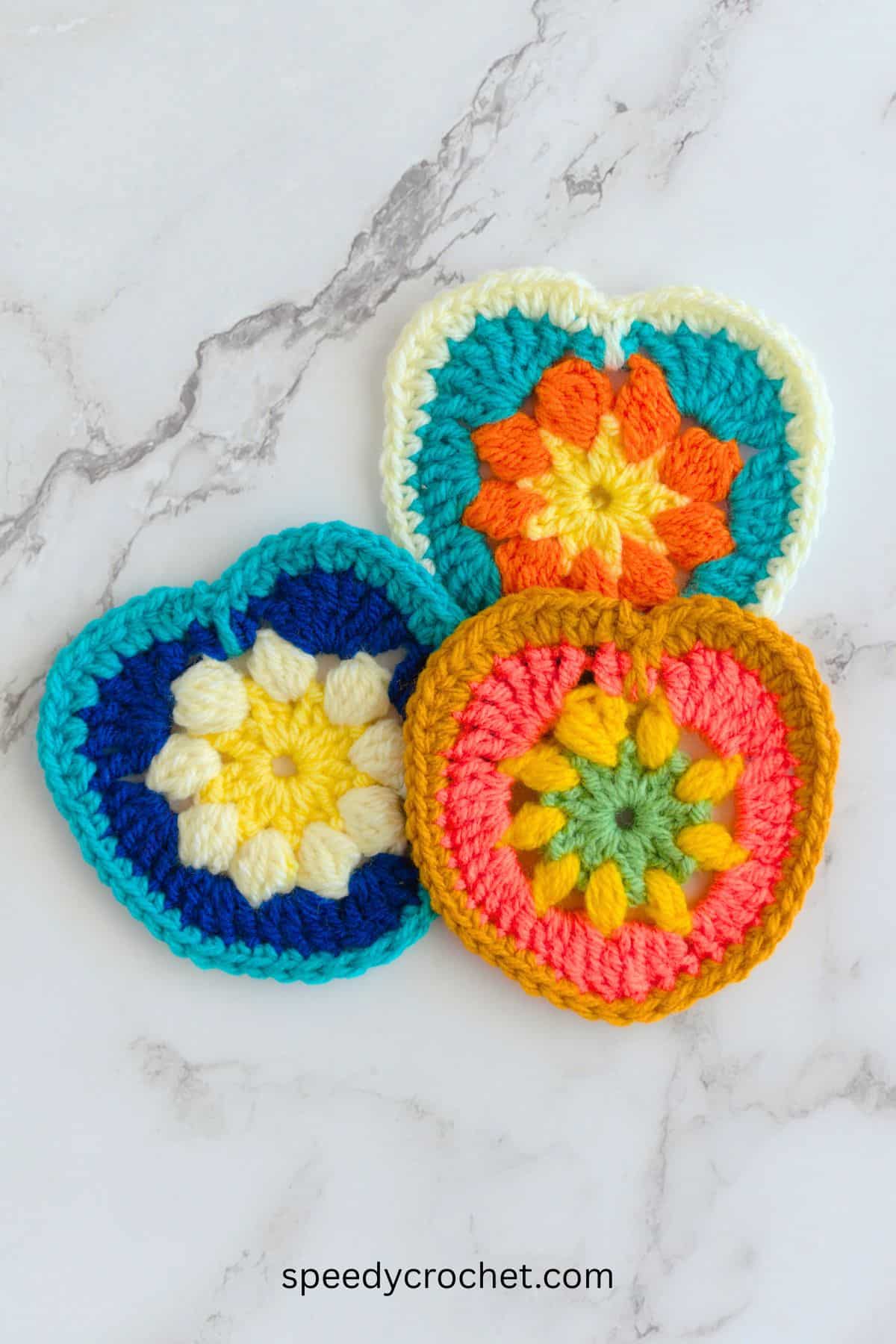 Three multi colored crochet hearts.