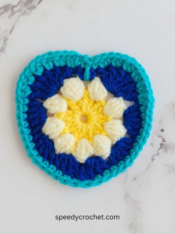 A blue crochet heart with a flower center.