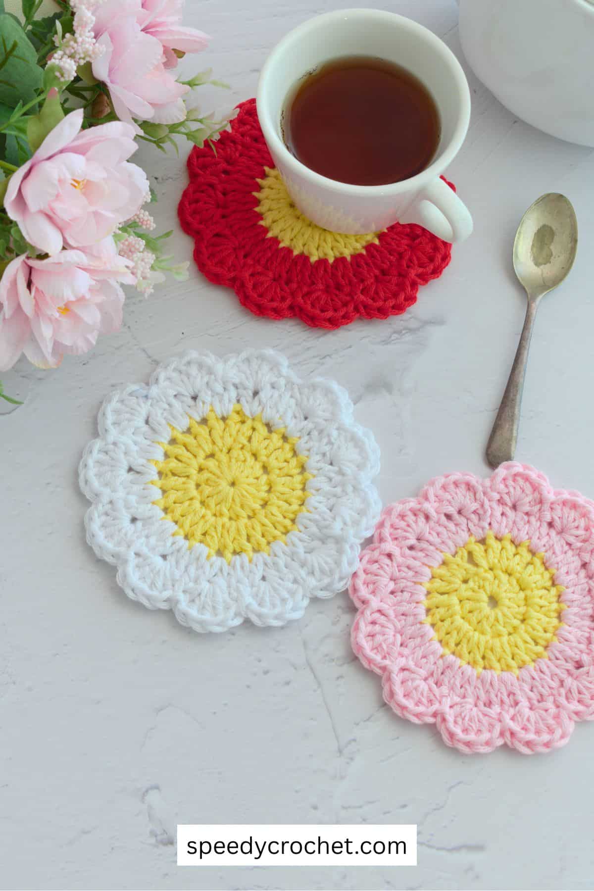 Three crochet daisy coasters in red, white and pink.
