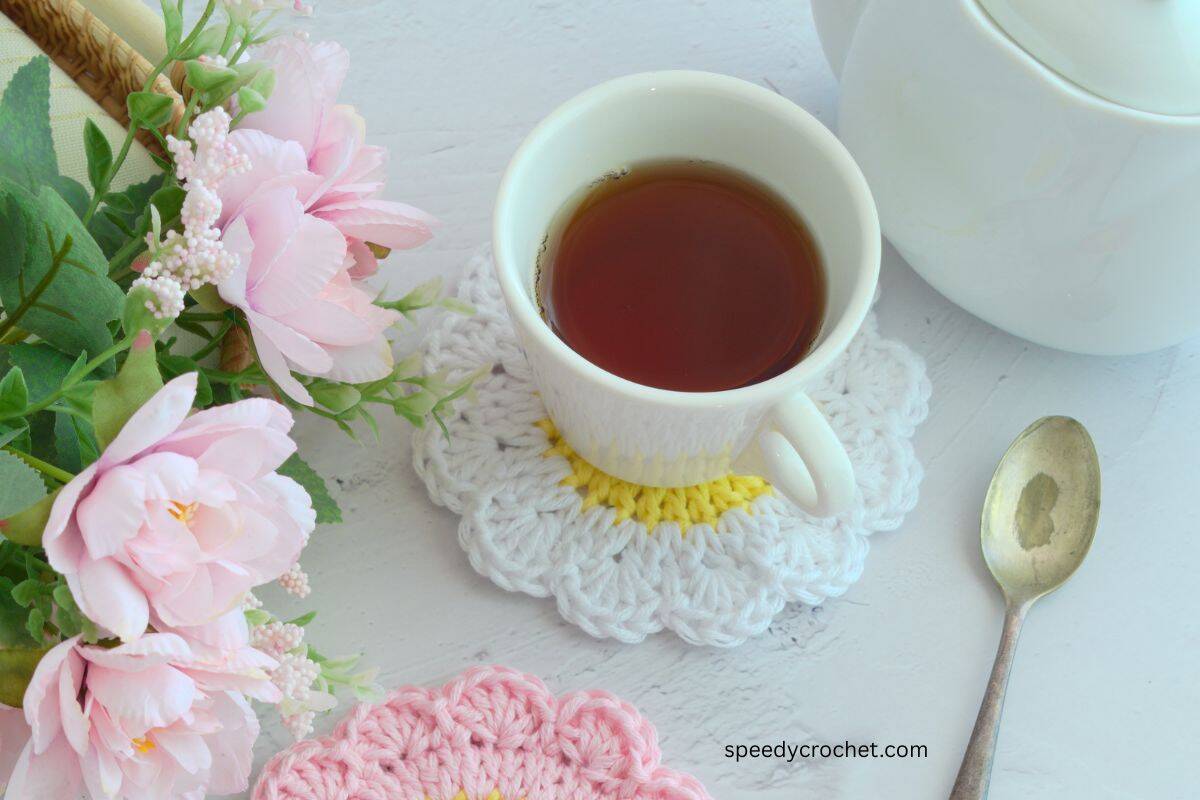 A tea cup on a white crochet coaster.