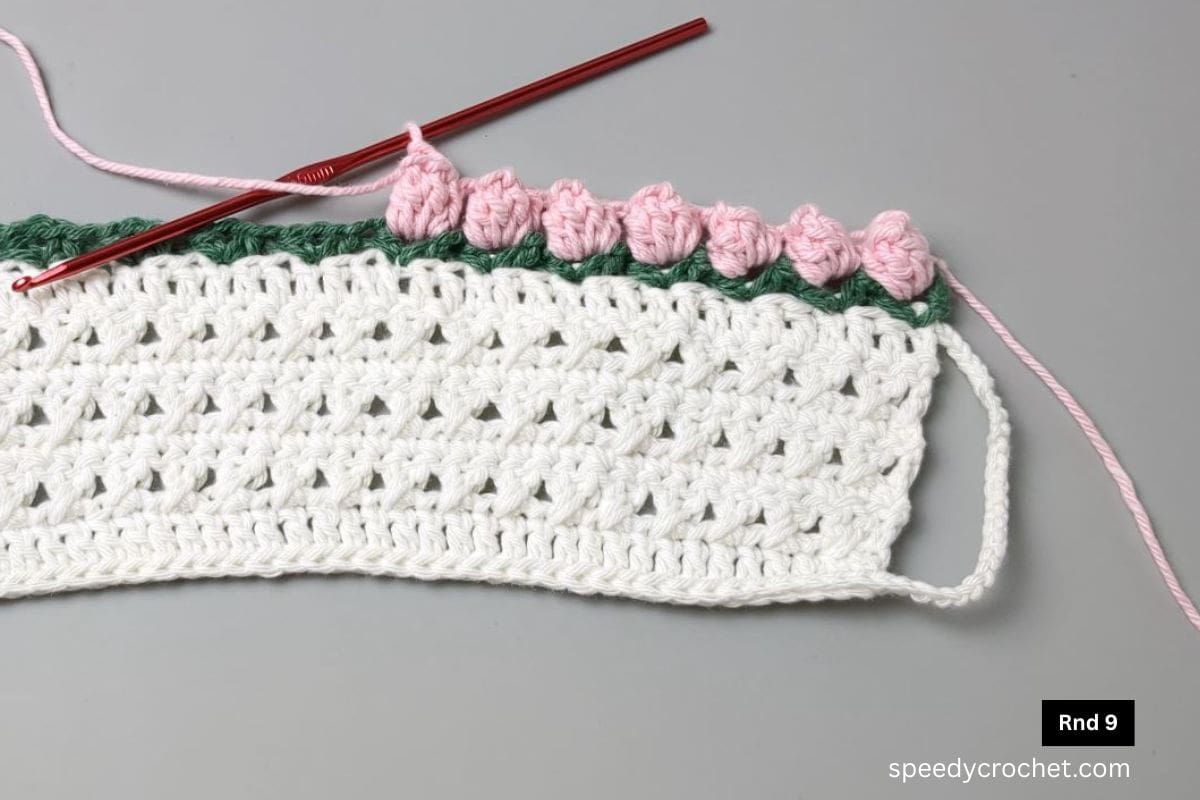 Pink crochet edging on a mug cozy.,