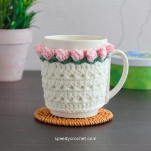 A white mug cozy with popcorn crochet edging.