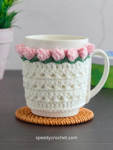 A white mug cozy with popcorn crochet edging.