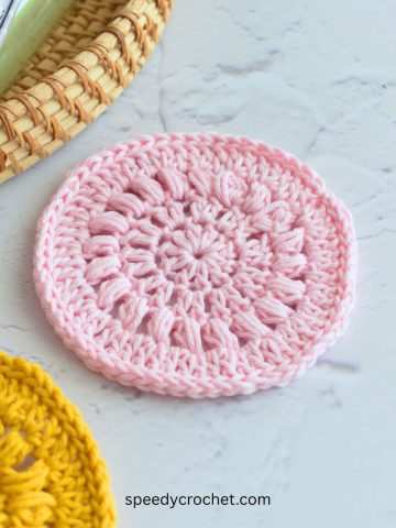 A pink flat round crochet circle.