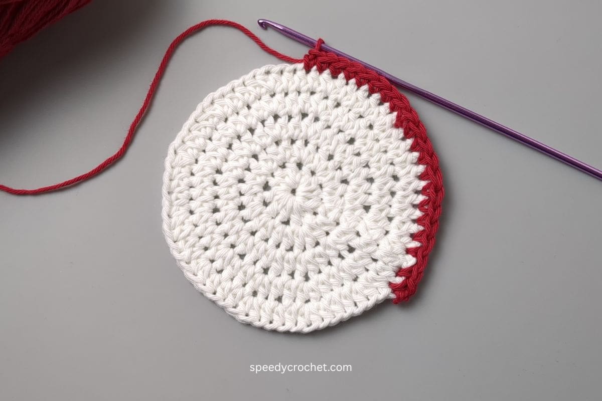 A white crochet circle with a red border.
