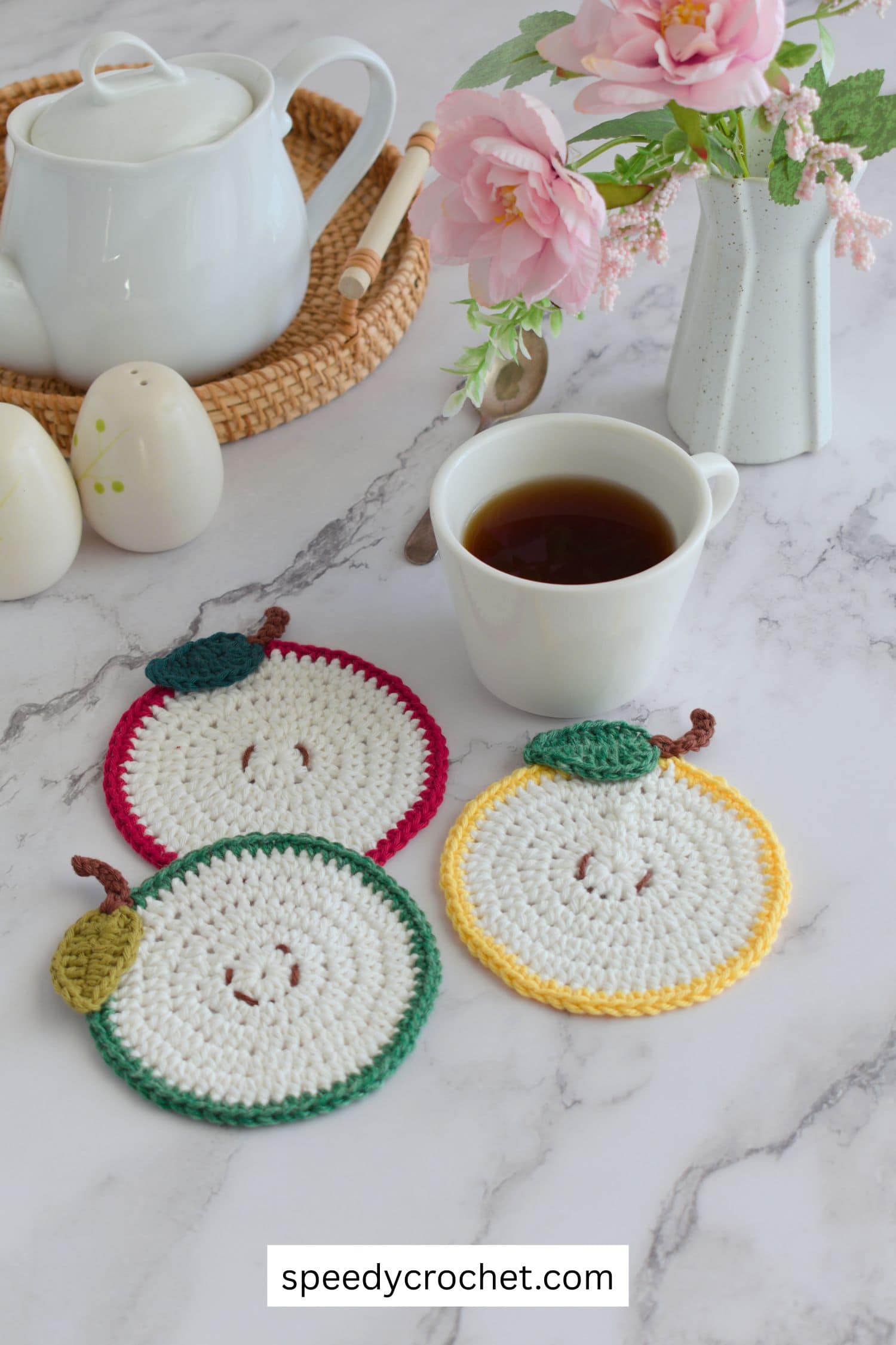 Three crochet apple coasters and a tea cup.