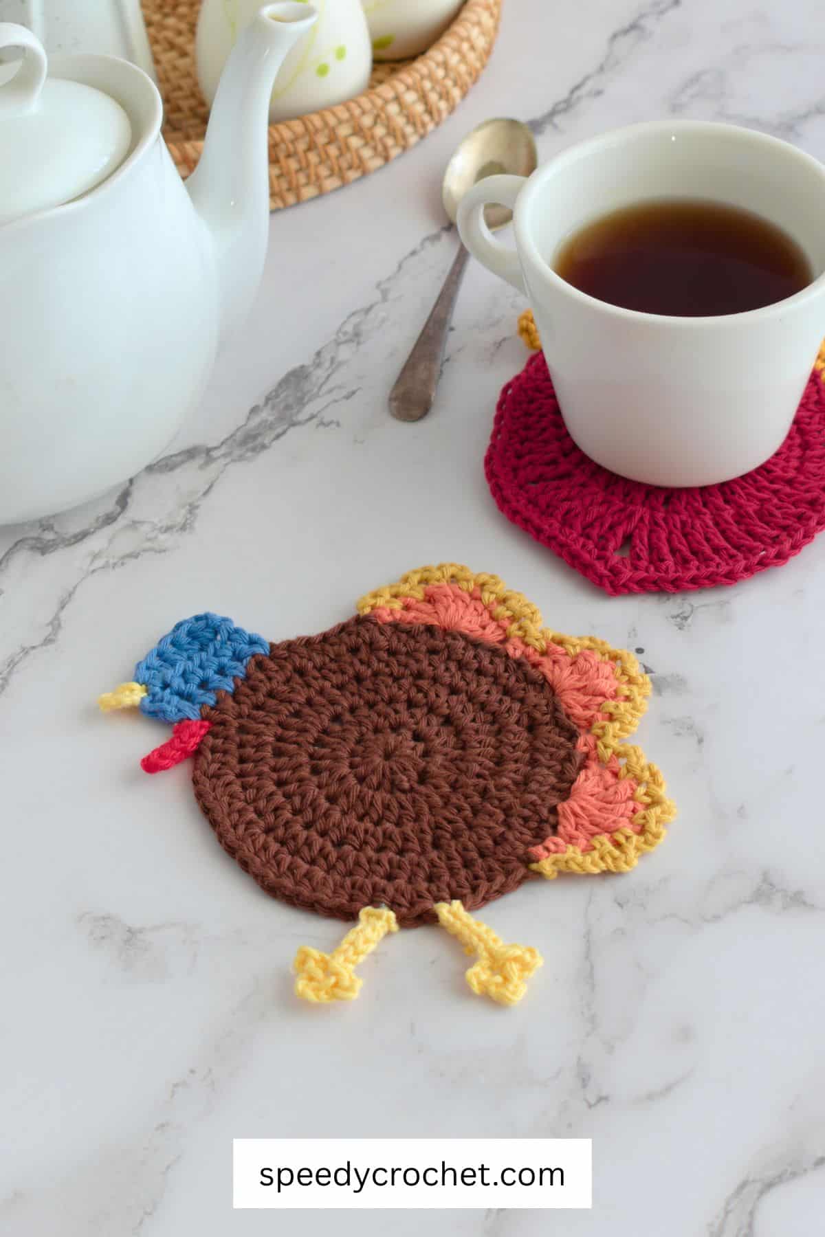 Turkey crochet coaster on a table with a mug.