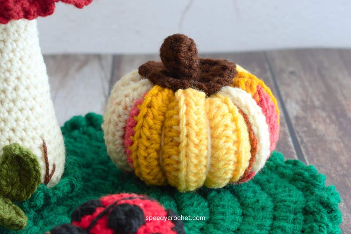 Crochet pumpkin on a green crochet table mat.